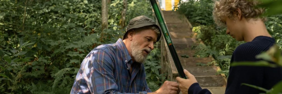 Grandfather and grandson preparing fishing rods outdoors, enjoying quality family time in nature.