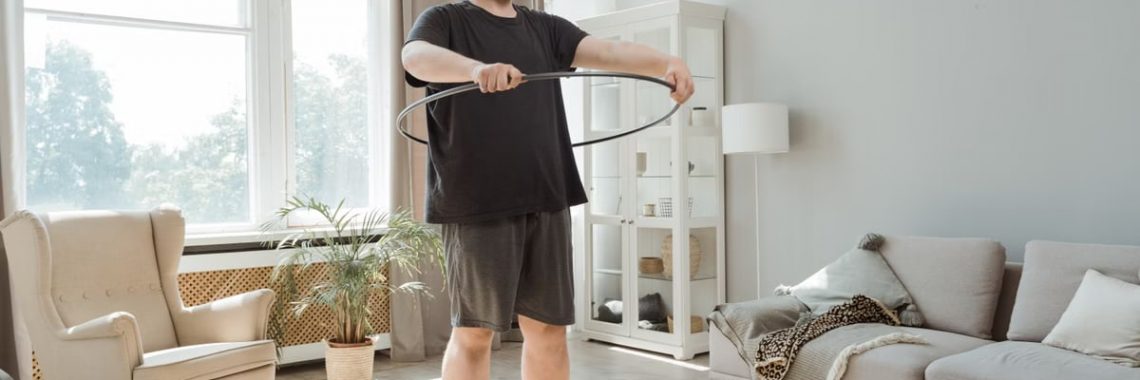 Man enjoying an indoor workout using a hula hoop for fitness and wellness.